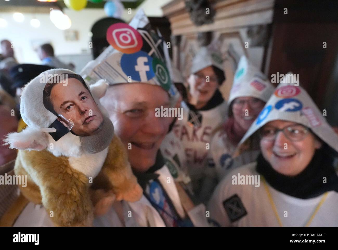 Marne, Deutschland. März 2025. Narren, die als Fake News gekleidet sind, und ein Schaf mit einem Foto von Elon Musk stehen im Rathaus vor dem Beginn der Rose Monday Parade der Marner Karnevals Gesellschaft (MKG) durch das Stadtzentrum. Die traditionelle Rosenmontagsparade gilt als absolutes Highlight des Straßenkarnevals in Schleswig-Holstein und zieht regelmäßig rund 20.000 Zuschauer an. Quelle: Marcus Brandt/dpa/Alamy Live News Stockfoto
