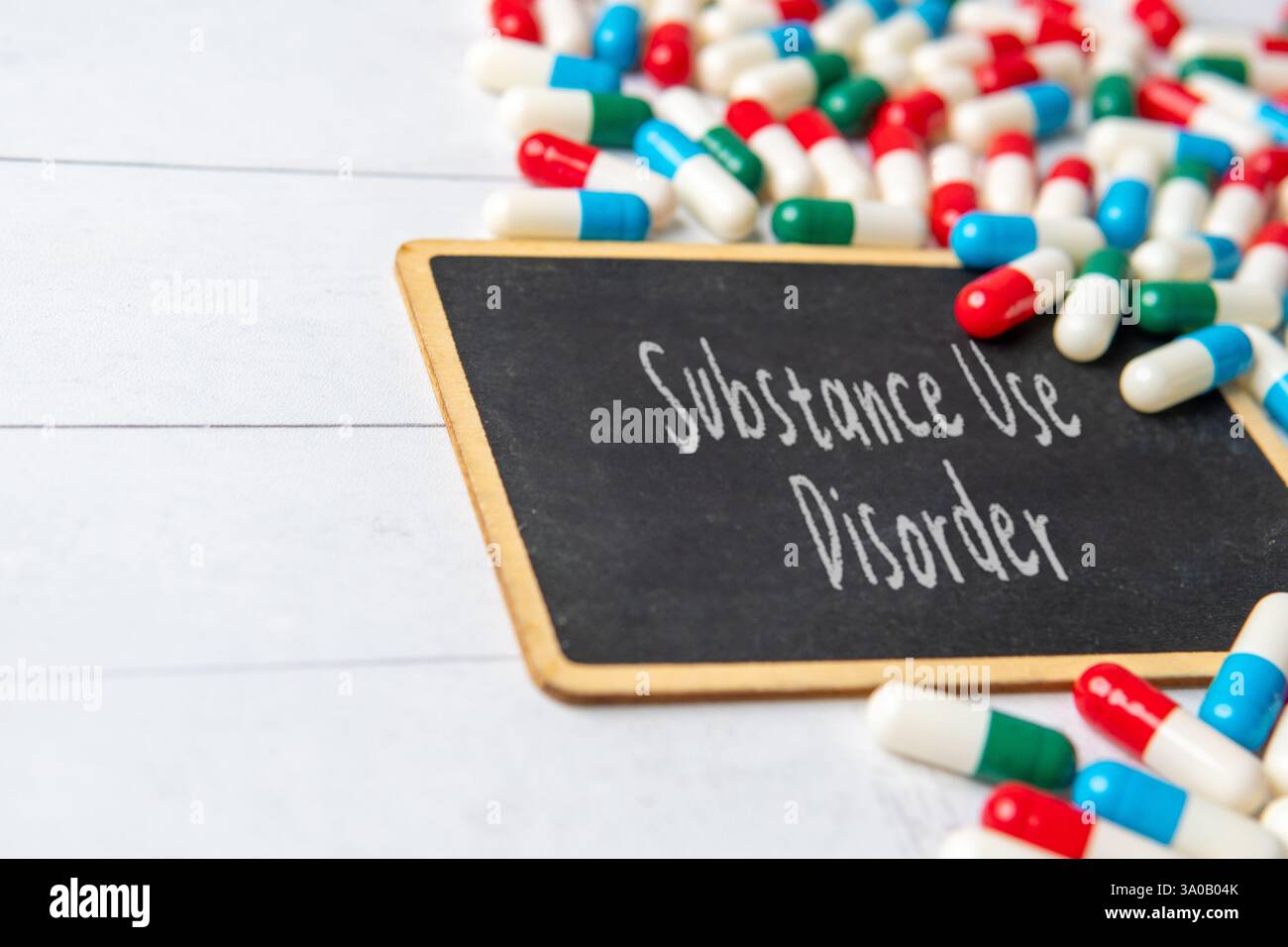 Eine Tafel mit dem Wort "Substanzmissbrauch", umgeben von verstreuten Pillen und Kapseln. Medizin- und Gesundheitskonzept. Stockfoto