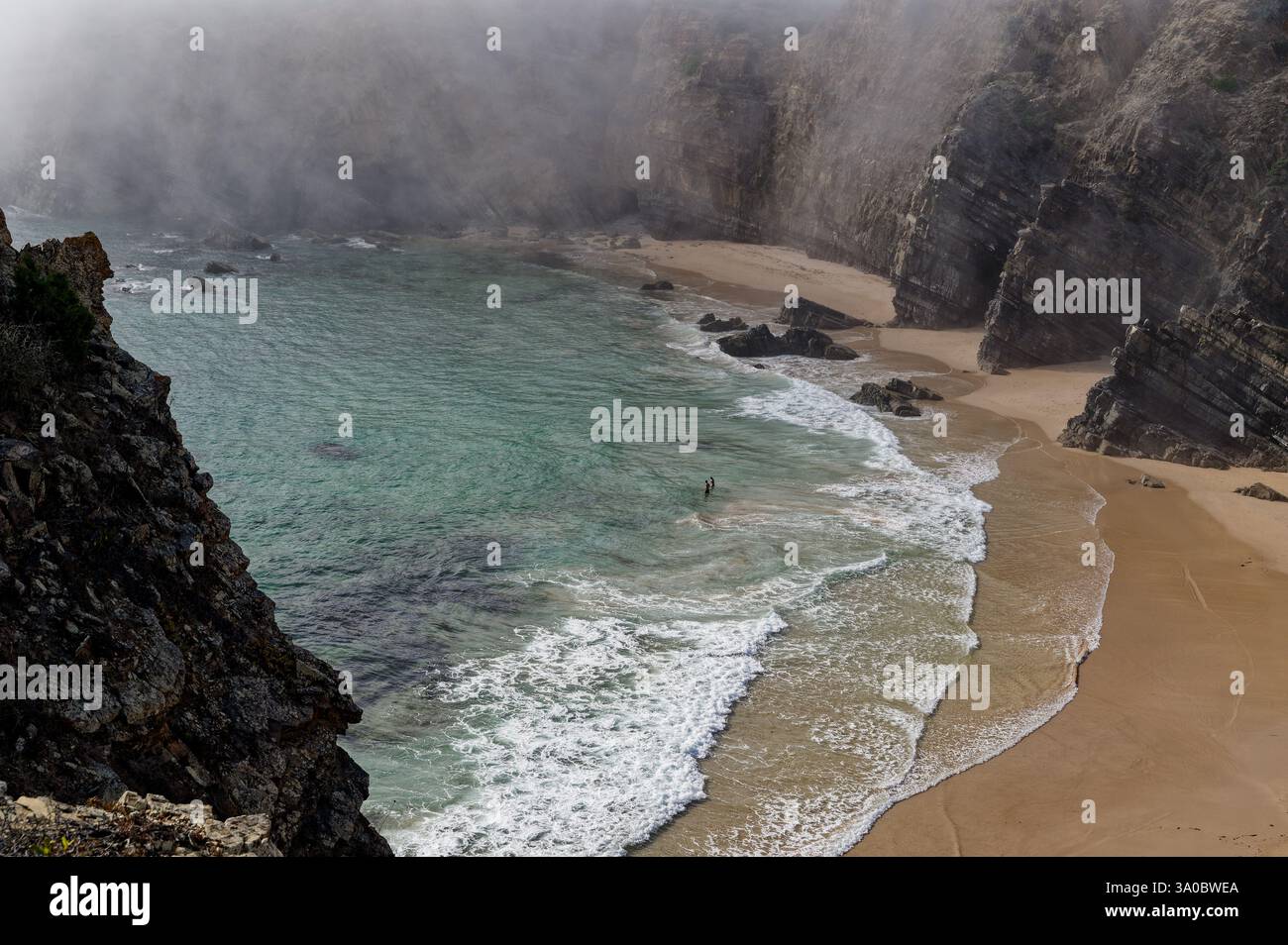 Nebel fällt über die zerklüfteten Klippen von Praia do Tonel, während sanfte Wellen die abgelegene Küste küssen Stockfoto