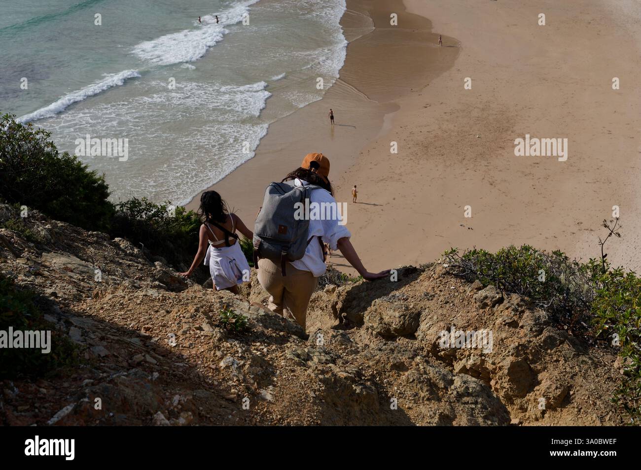Die Wanderer steigen auf einem zerklüfteten Küstenpfad in Richtung des goldenen Sandes von Praia do Tonel ab Stockfoto