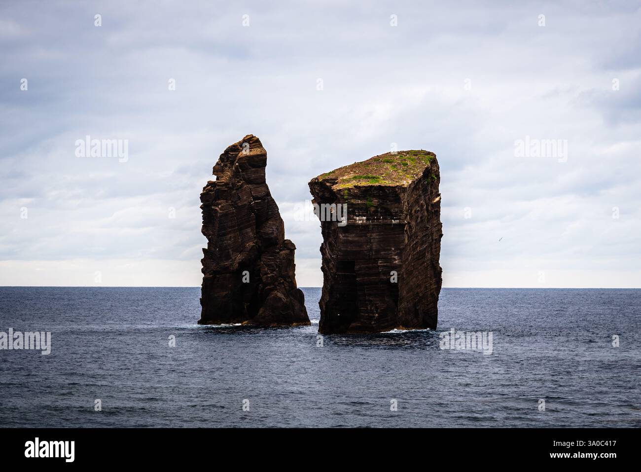 Zwei felsige Inselchen stehen hoch im Atlantik unter einem bewölkten Himmel und bilden eine dramatische Meereslandschaft in der Nähe von Praia dos Mosteiros auf den Azoren. Stockfoto