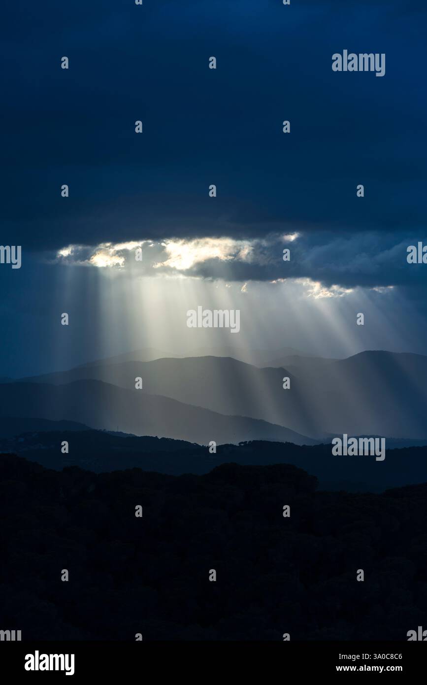 SONNENSTRAHLEN DURCH DUNKLE STURMWOLKEN ÜBER DEN KÜSTENBERGEN PALAFOLLS MARESME BARCELONA PROVINZ KATALONIEN SPANIEN Stockfoto