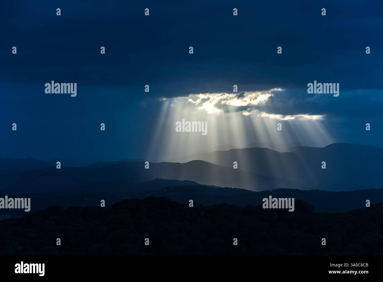 SONNENSTRAHLEN DURCH DUNKLE STURMWOLKEN ÜBER DEN KÜSTENBERGEN PALAFOLLS MARESME BARCELONA PROVINZ KATALONIEN SPANIEN Stockfoto