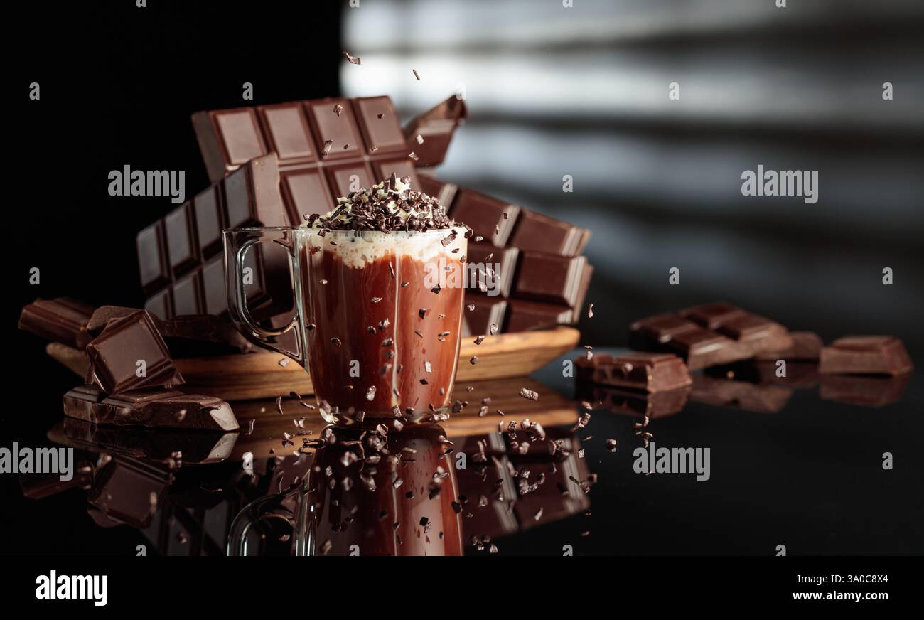 Heiße Schokolade mit Schlagsahne, bestreut mit Schokoladenbrösel. Auf einem Hintergrund zerbrochene Bitterschokoladentafeln. Schwarzer reflektierender Hintergrund. Stockfoto