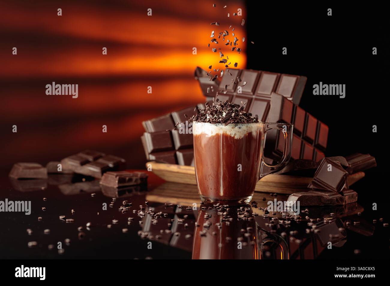 Heiße Schokolade mit Schlagsahne, bestreut mit Schokoladenbrösel. Auf einem Hintergrund zerbrochene Bitterschokoladentafeln. Schwarzer reflektierender Hintergrund. Stockfoto