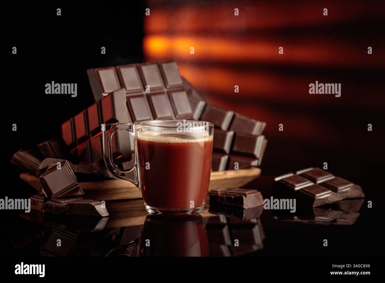 Tasse heiße Schokolade gegen zerbrochene Bitterschokoladentafeln. Der schwarze Hochglanzhintergrund sorgt für Tiefe und Reflexion. Kopierbereich. Stockfoto