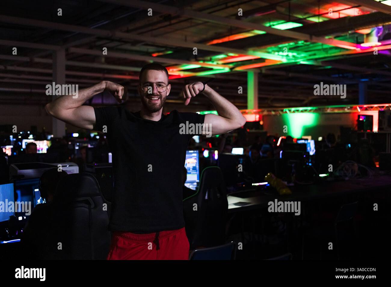 Junger Mann, ein Gamer beim digitalen Festival, der im Computerraum steht und in die Kamera schaut. Gaming-Lifestyle und Community-Konzepte. Stockfoto