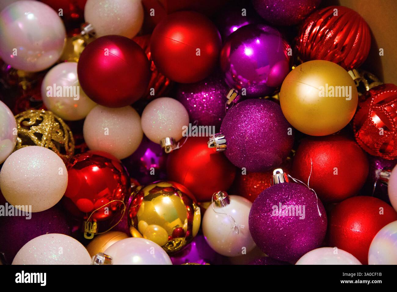 Nahaufnahme farbenfroher Weihnachtsbaumschmuck in Rot-, Gold- und Rosa-Tönen zur Dekoration eines Weihnachtsbaums. Stockfoto