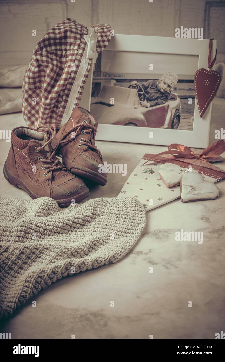 Das erste Paar Schuhe, Foto, Hut und andere Erinnerungen an Kindheit und Kindheit, Vintage-Stil, vertikal mit Kopierraum Stockfoto