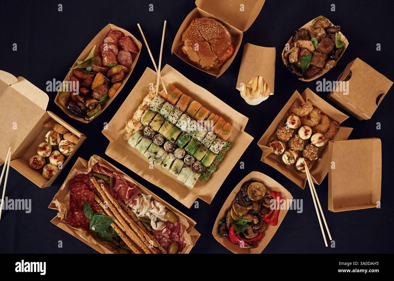 Blick von oben auf den Tisch mit Essen darauf. Fleisch, Gemüse, Sushi, Pommes frites, Burger, Pilze. Stockfoto