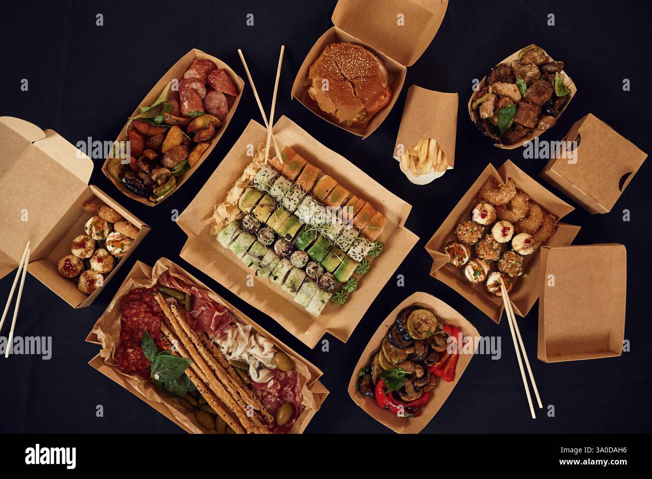 Blick von oben auf den Tisch mit Essen darauf. Fleisch, Gemüse, Sushi, Pommes frites, Burger, Pilze. Stockfoto
