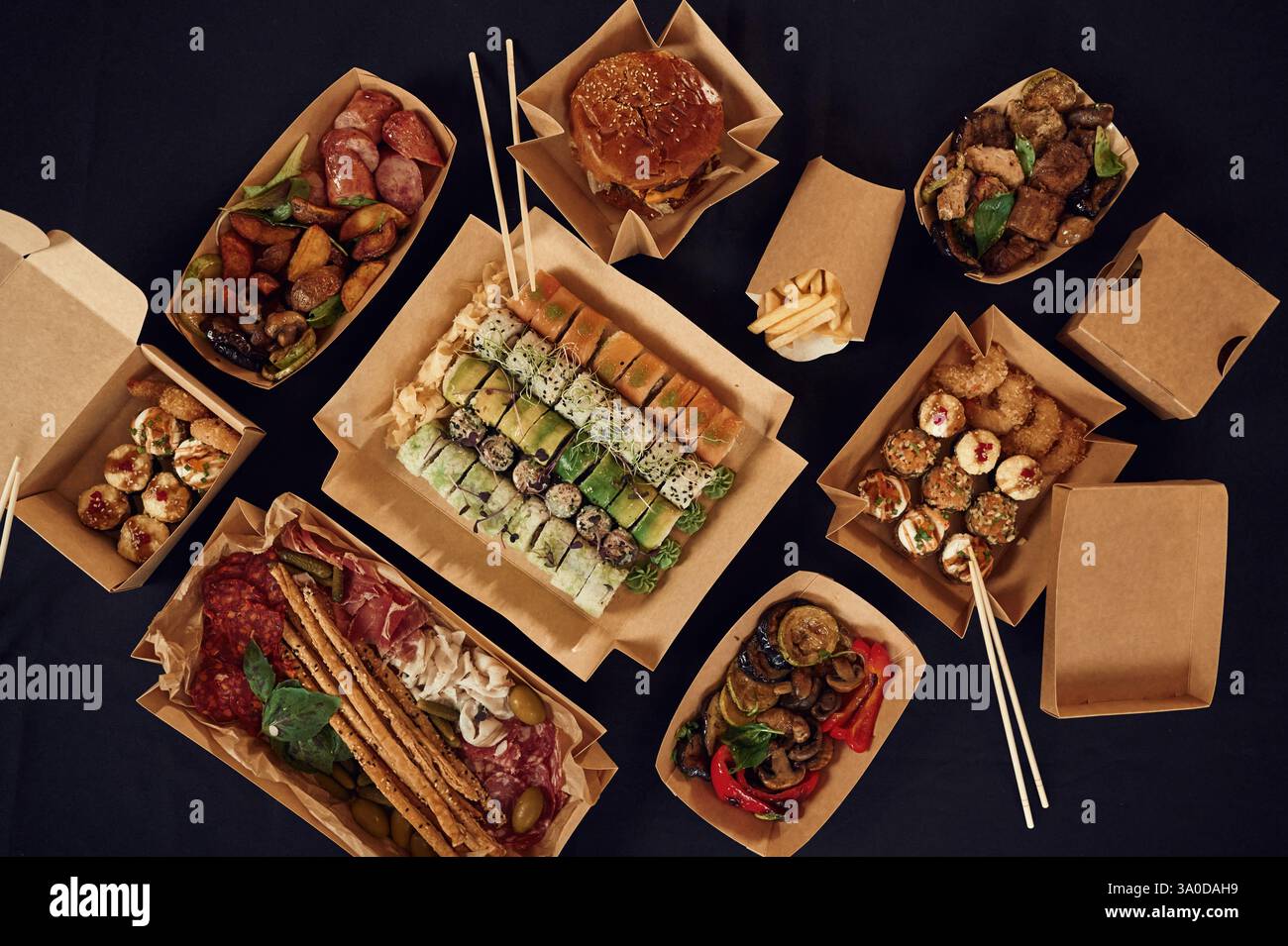 Blick von oben auf den Tisch mit Essen darauf. Fleisch, Gemüse, Sushi, Pommes frites, Burger, Pilze. Stockfoto