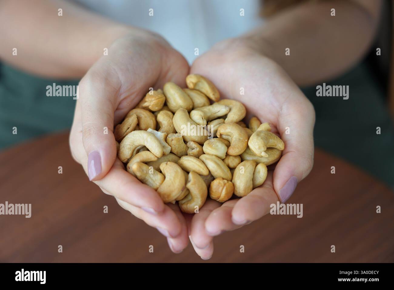 Cashewnüsse. Nahaufnahme weiblicher Hände mit einem Haufen Cashewnüsse. Stockfoto