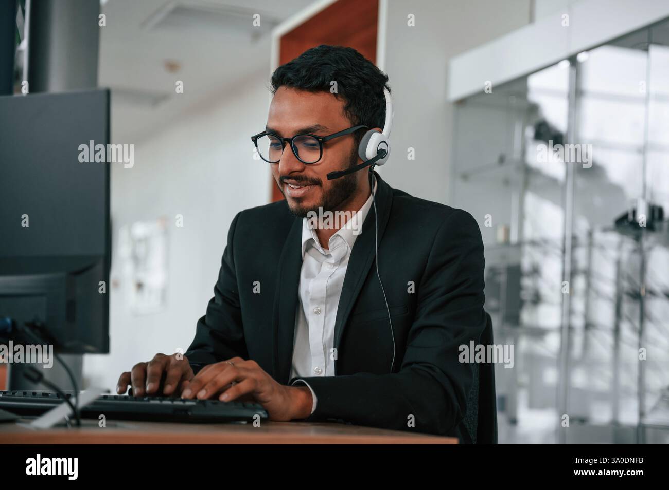 Der indische Mann sitzt und arbeitet im Autohaus. Stockfoto