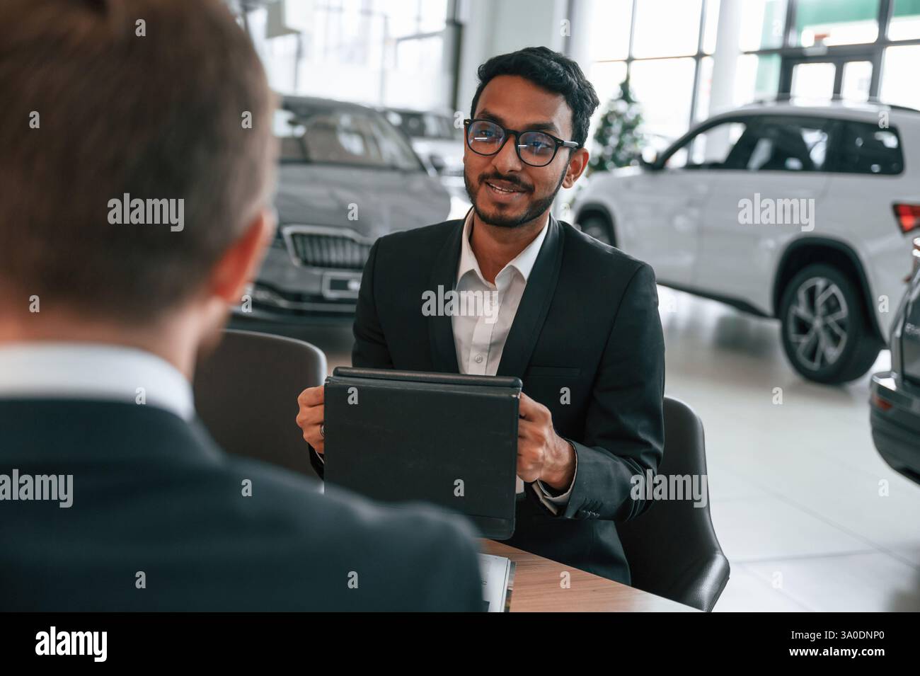 Zwei Geschäftsleute arbeiten im Autohaus zusammen. Stockfoto