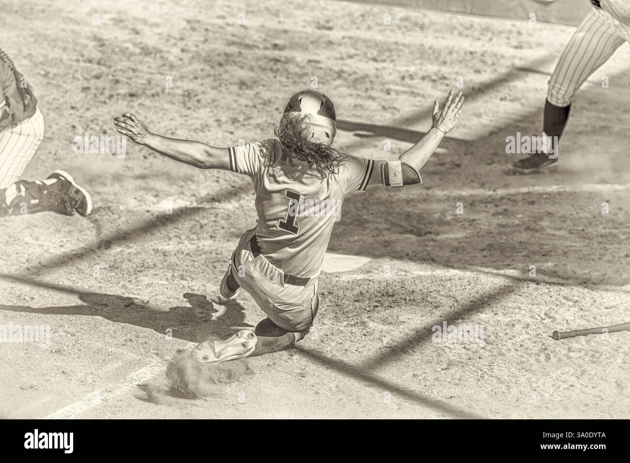 Ein Softball-Spieler gleitet auf der Startplatte Stockfoto