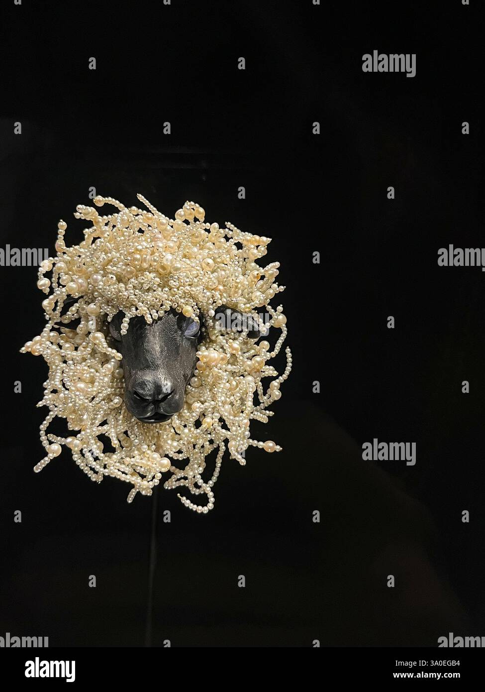 Eine künstlerische Darstellung eines wunderschön gestalteten Schafskopfes mit lockigen Details vor einem dunklen, markanten Hintergrund Stockfoto
