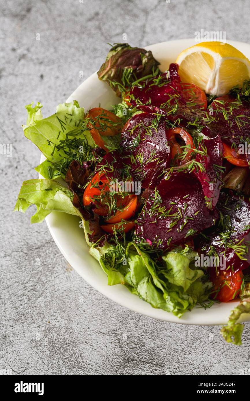 Rote-Bete-Salat mit Gemüse, Tomaten und Dill auf einem Steintisch Stockfoto