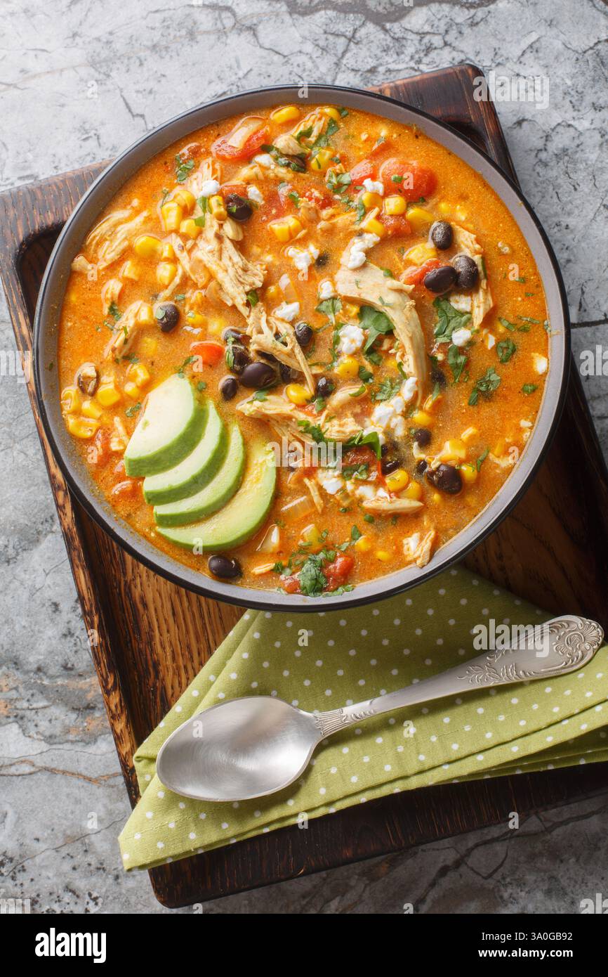 Hühnchen Enchilada Suppe ist cremig, dick, sehr angenehm, und köstliche Nahaufnahme auf dem Teller auf dem Tisch. Vertikale Draufsicht von oben Stockfoto