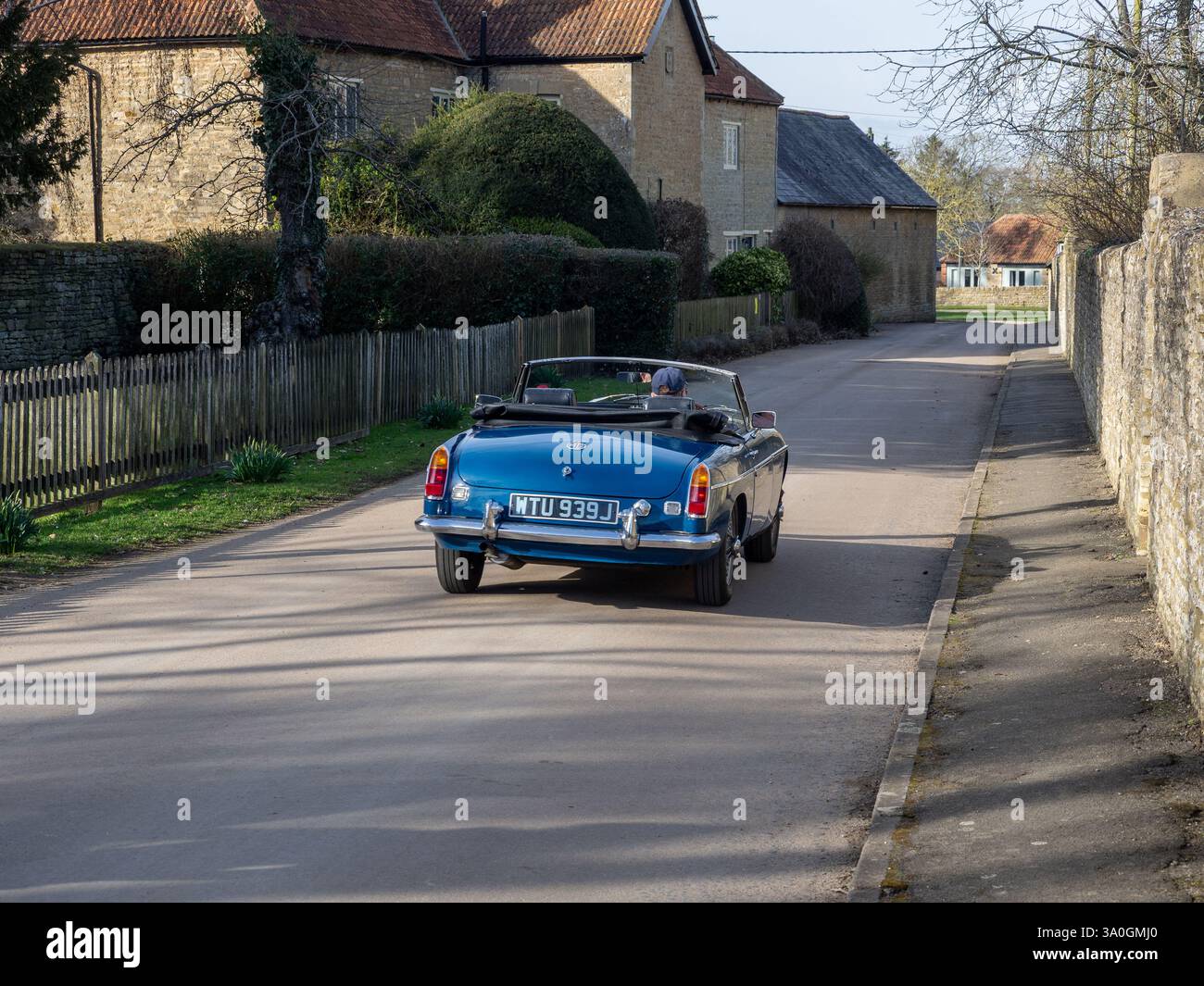 MG Roadster fährt durch das Dorf Castle Ashby, Northamptonshire, Großbritannien Stockfoto