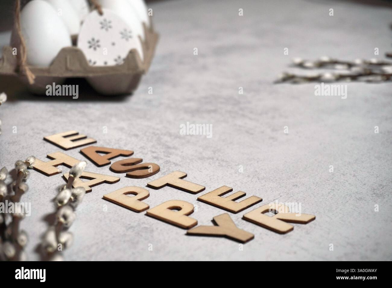 Der ostertext-Titel mit Faden und Zweigen oder Muschi-Zweigen Weide und Eiern im Pappschachtel-Flatlay-Konzept. Naturrahmen auf hellem Hintergrund Stockfoto