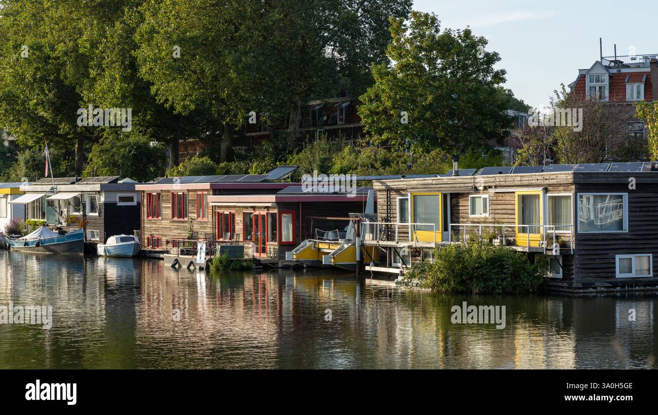 Hausboote mit Solarpaneelen auf dem Dach des Hausbootes an einem grauen Tag mit niedriger Sonne, die im Wasser reflektiert. Stockfoto