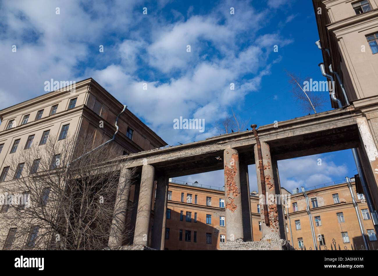 Ein historisches beschädigtes Gebäude mit rustikalen architektonischen Details, unter einem klaren Himmel mit weichen Wolken. Die Fassade weist Anzeichen von Verschleiß auf, die an das erinnern Stockfoto