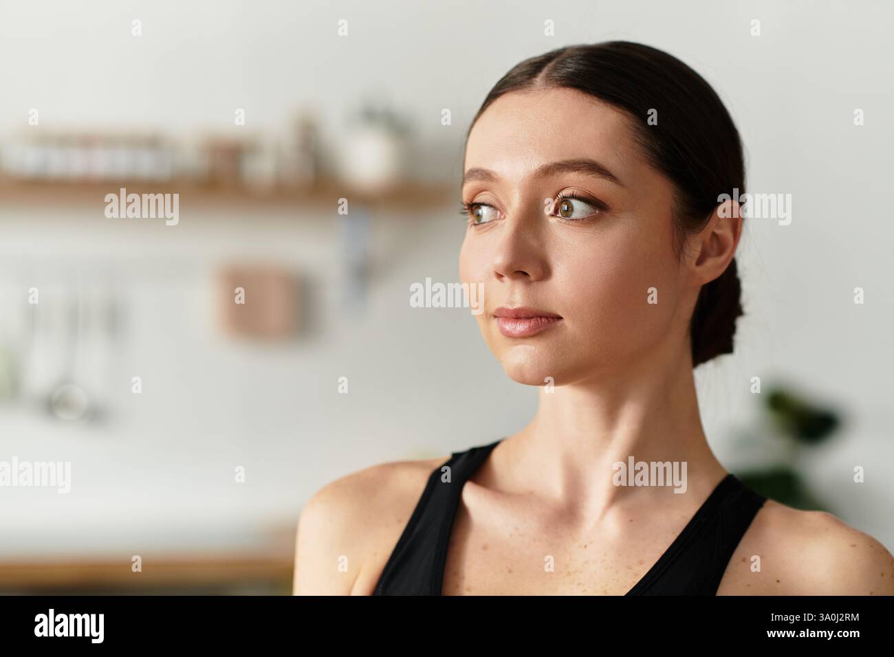 Schöne junge Frau übt in schwarzer Sportkleidung in ihrem modernen Wohnraum. Stockfoto