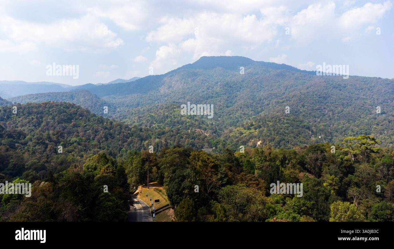 Aus der Vogelperspektive des Doi Suthep-Pui Nationalparks in Chiang Mai, Thailand, mit üppigem Wald, gewundenen Straßen und majestätischen Bergen unter einer bewölkten Wolke Stockfoto