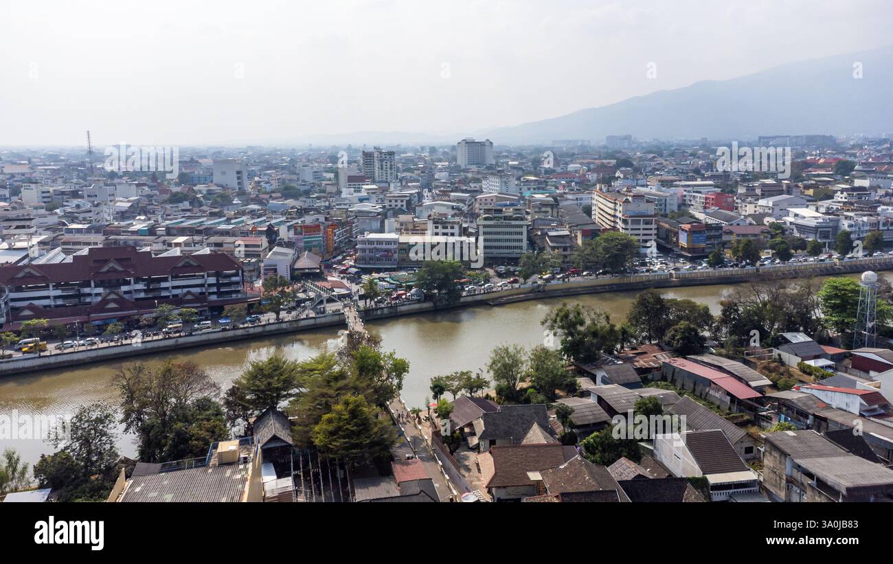 Aus der Vogelperspektive der Stadt Chiang Mai mit dem Fluss Ping, der das Stadtzentrum und den Berg Doi Suthep im Hintergrund durch Verschmutzung überquert Stockfoto