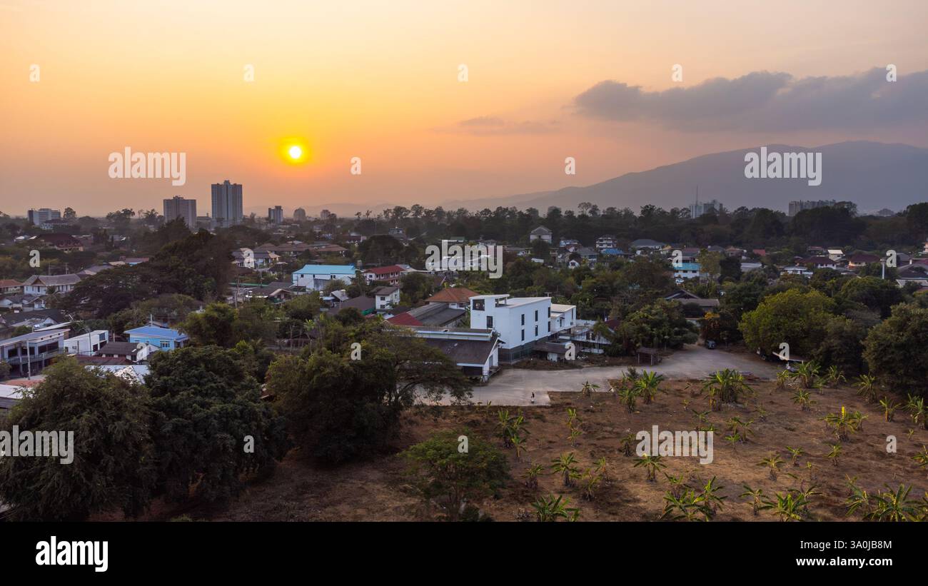 Aus der Vogelperspektive der Stadt Chiang Mai mit dem Berg Doi Suthep im Hintergrund bei einem lebhaften Sonnenuntergang mit Verschmutzung Stockfoto