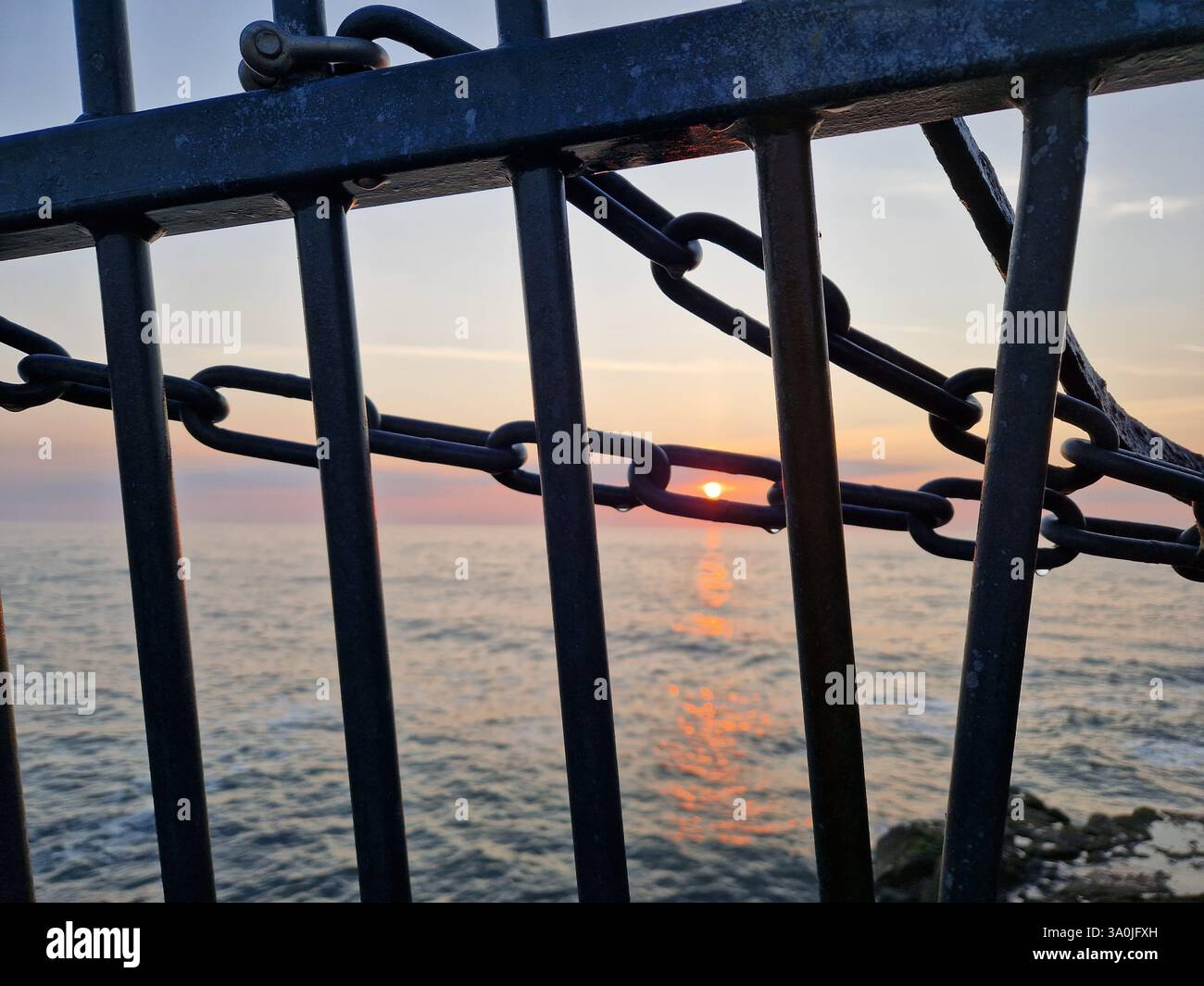 Goldener Sonnenaufgang über Seaham Beach an einem warmen Sommermorgen, der ein ruhiges Leuchten über die ruhigen Wellen wirft. - Smartphone-aufgenommenes Stockfoto