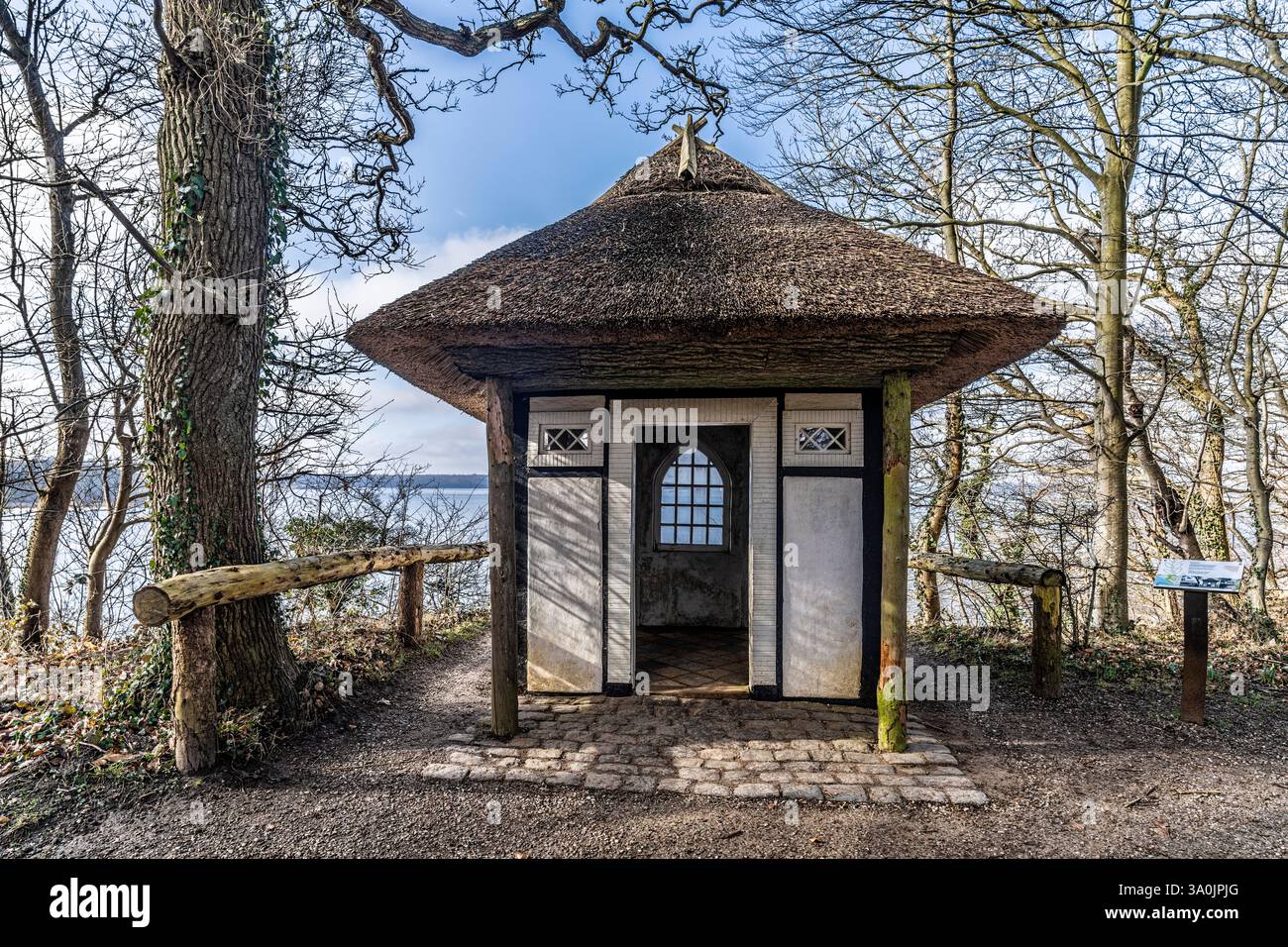 Eine malerische strohgedeckte Hütte inmitten von Bäumen an einem malerischen Ufer, die natürliche Ruhe bietet. Stockfoto