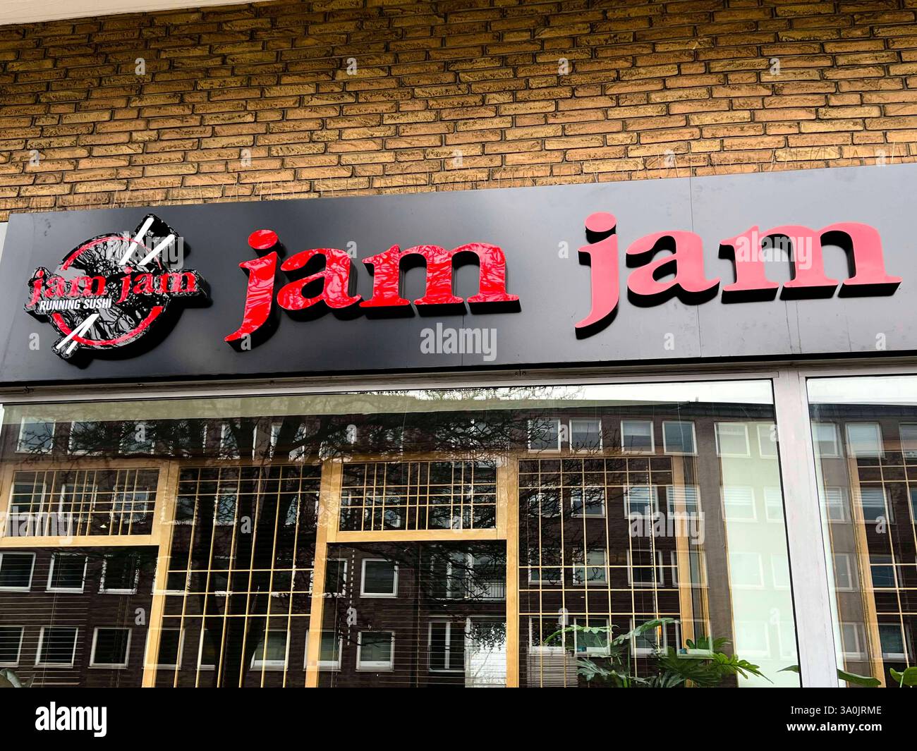 Jam Jam Logo Buchstaben an der Hauswand des Lokalin Hamburg Wandsbek - Kaiten Zushi ummlaufende Sushi werden japanische Restaurants für Sushi bezeichnet, bei denen die Speisen auf einem rundlaufenden Fließband angeboten werden haeufig auch als Running-Sushi bezeichnet. Hamburg Deutschland *** Jam Jam Jam Logo Buchstaben an der Wand des Restaurants in Hamburg Wandsbek Kaiten Zushi Running Sushi ist der Name japanischer Sushi-Restaurants, in denen das Essen auf einem Drehförderband serviert wird Stockfoto