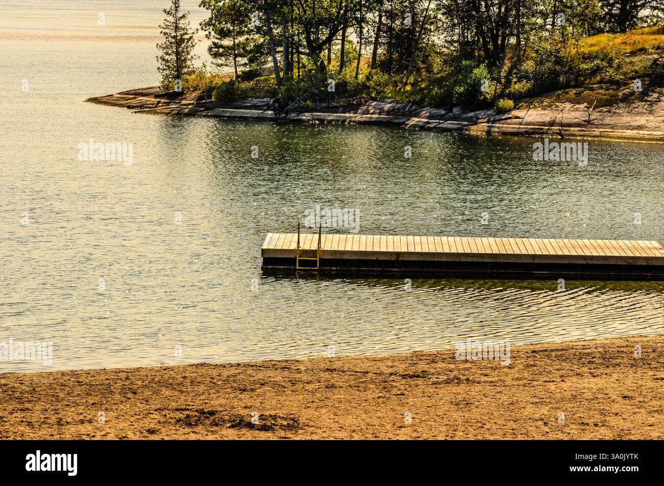 Leeres Dock im frühen Herbst Sonnenlicht zwischen einem Strand und einer Insel am St. Lawrence River Stockfoto