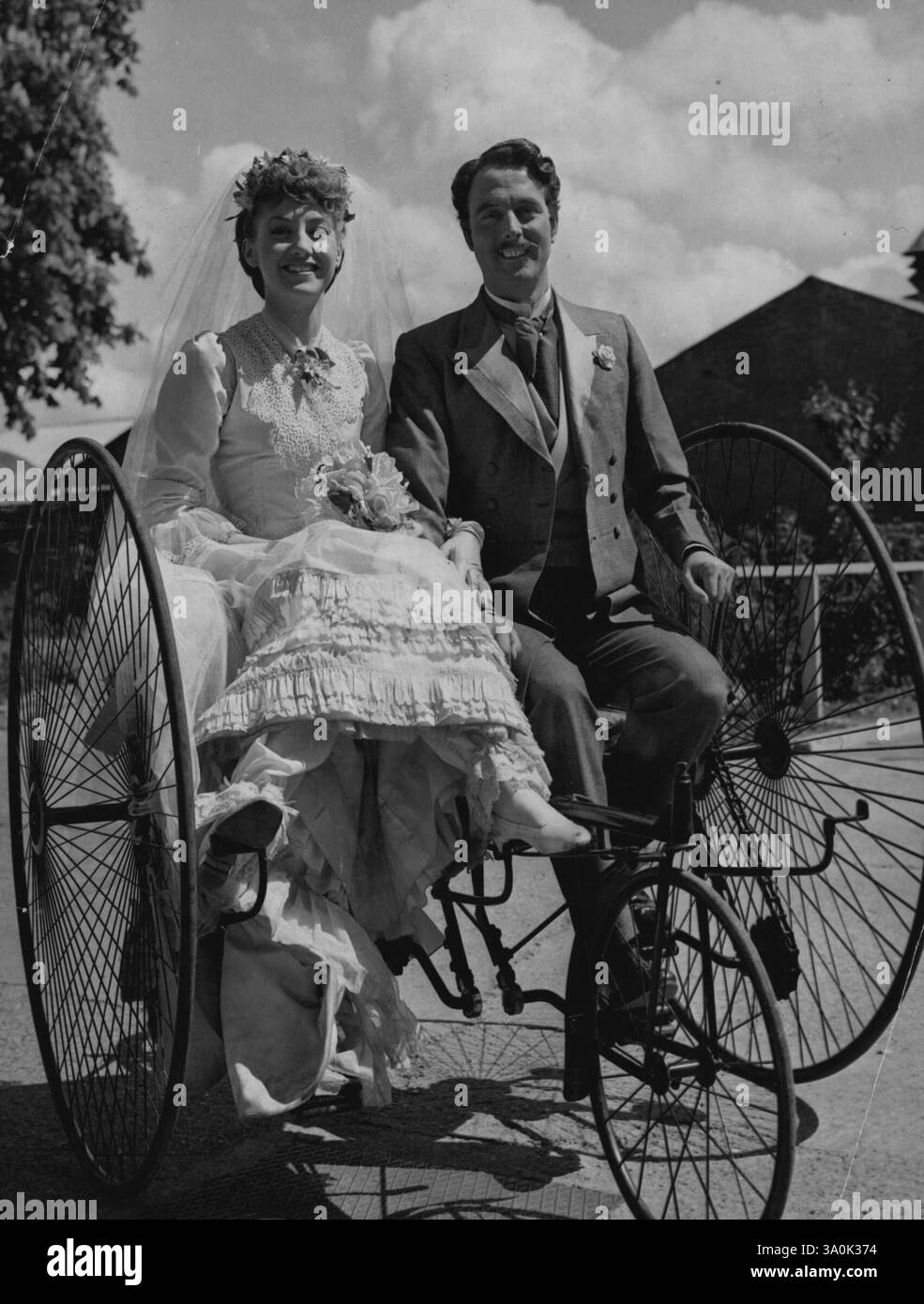 Bei diesen alten Zweirädern -- 'Soziables' nannten sie sie - musste man nur freundlich sein. Vielleicht ist das der Grund, warum die Scheidung in den viktorianischen Tagen so viel seltener war. Hier beweisen Yvonne Marsh und Tom Round, dass es schwierig gewesen sein muss, getrennte Wege zu gehen. Sie sind verdrehte Braut und „herzlose“ Angeklagte in der Sequenz „Trial by Jury“ aus dem Film „Gilbert and Sullivan“ - aber es gab keinen Unterschied, als sie die „Kutsche für zwei Personen“ versuchten, die die Londoner Filmstudios in Shepperton nutzen, um der Produktion viktorianische Authentizität zu verleihen. 18. April 1953. (Foto von Reuterp Stockfoto
