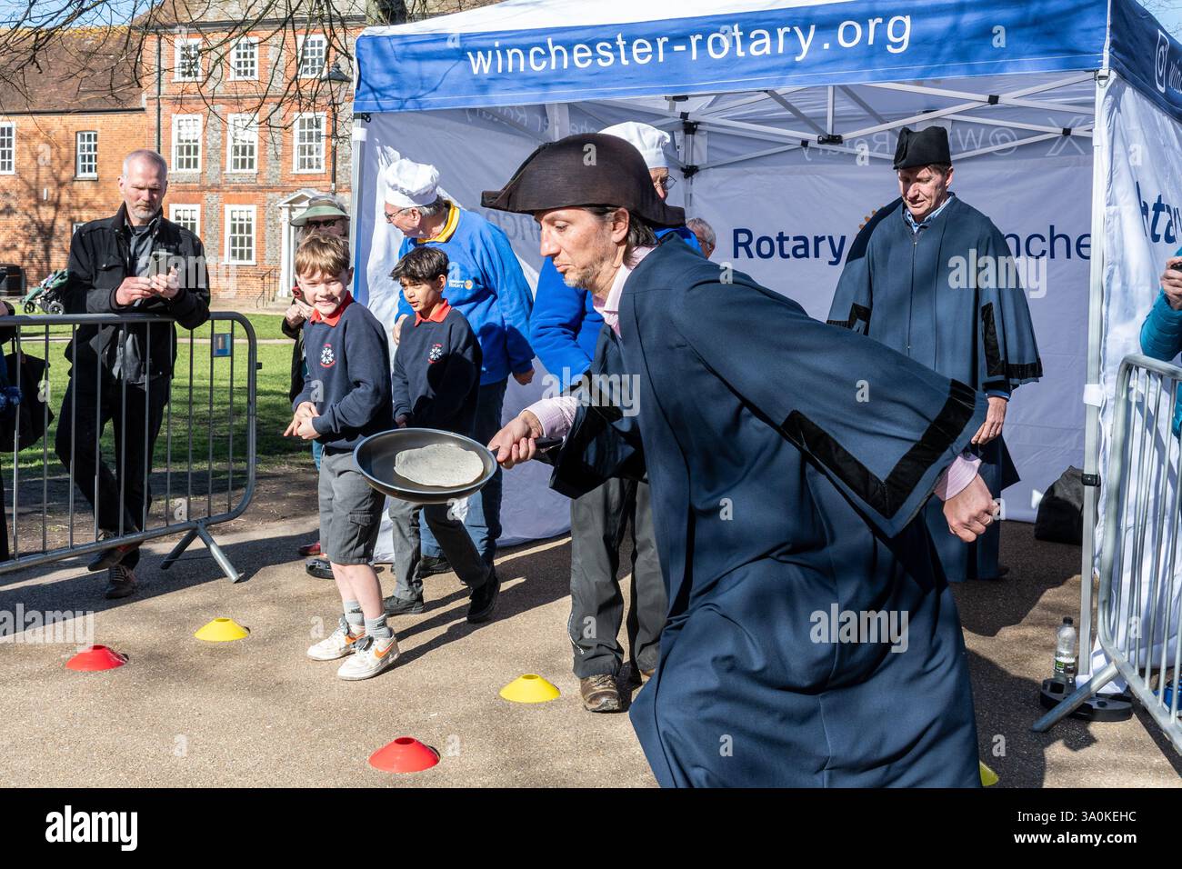 März 2025. Das jährliche Fastnacht-Pancake-Rennen fand heute in Winchester statt. Die vom Rotary Club in Zusammenarbeit mit der Winchester Cathedral organisierten Rennen, um Geld für wohltätige Zwecke zu sammeln, fanden an einem sonnigen Frühlingstag vor der Kathedrale statt. Stockfoto