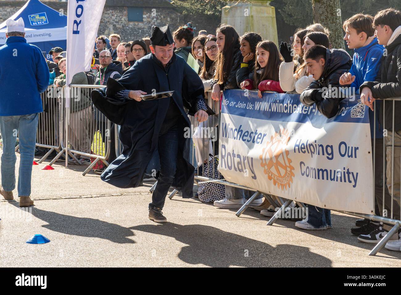 März 2025. Das jährliche Fastnacht-Pancake-Rennen fand heute in Winchester statt. Die vom Rotary Club in Zusammenarbeit mit der Winchester Cathedral organisierten Rennen, um Geld für wohltätige Zwecke zu sammeln, fanden an einem sonnigen Frühlingstag vor der Kathedrale statt. Stockfoto