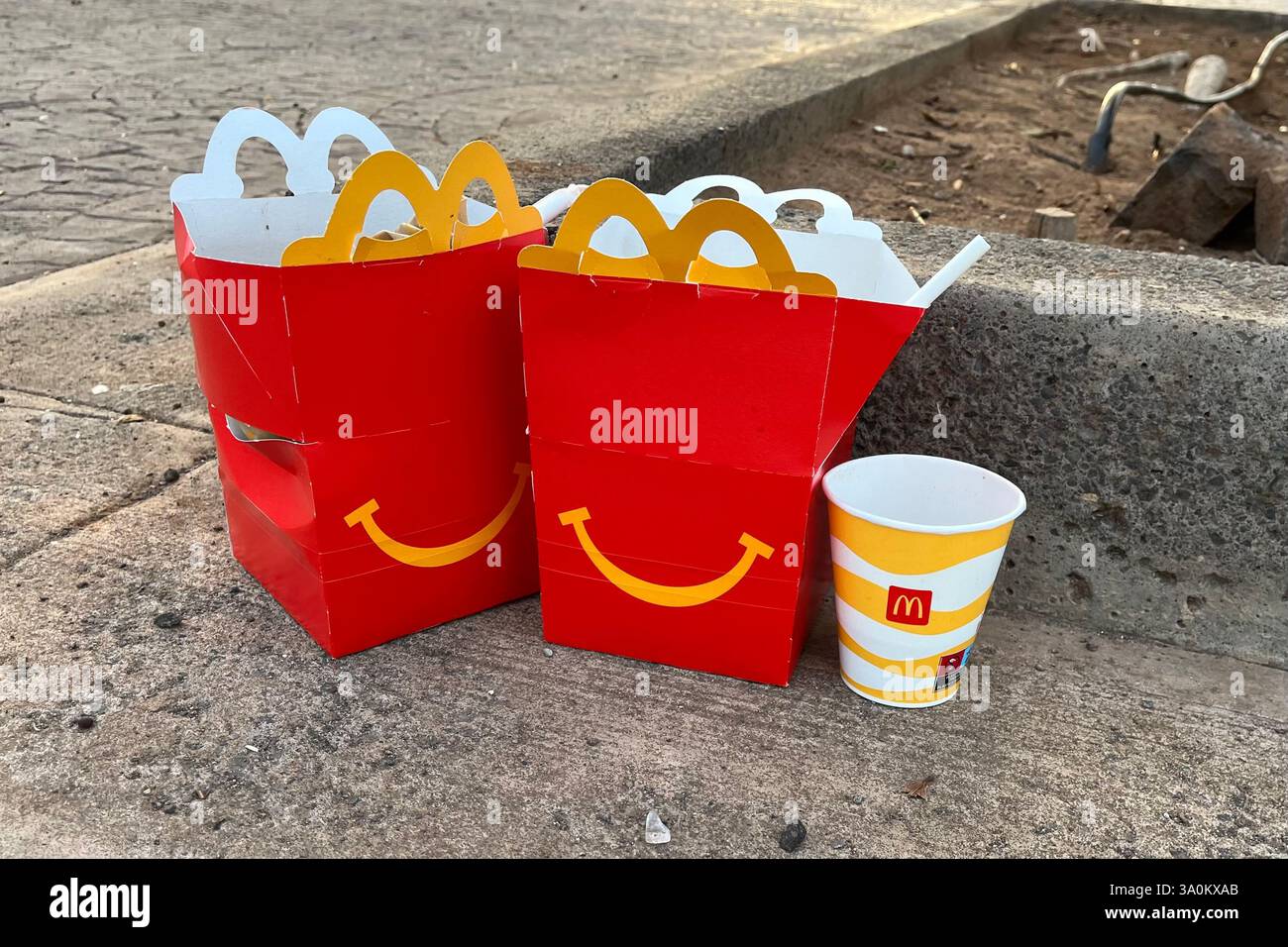 Zwei weggeworfene McDonalds Happy Meal Boxen und ein leerer McDonalds Drink Becher. Teneriffa, Kanarische Inseln, Spanien. Januar 2025. Stockfoto