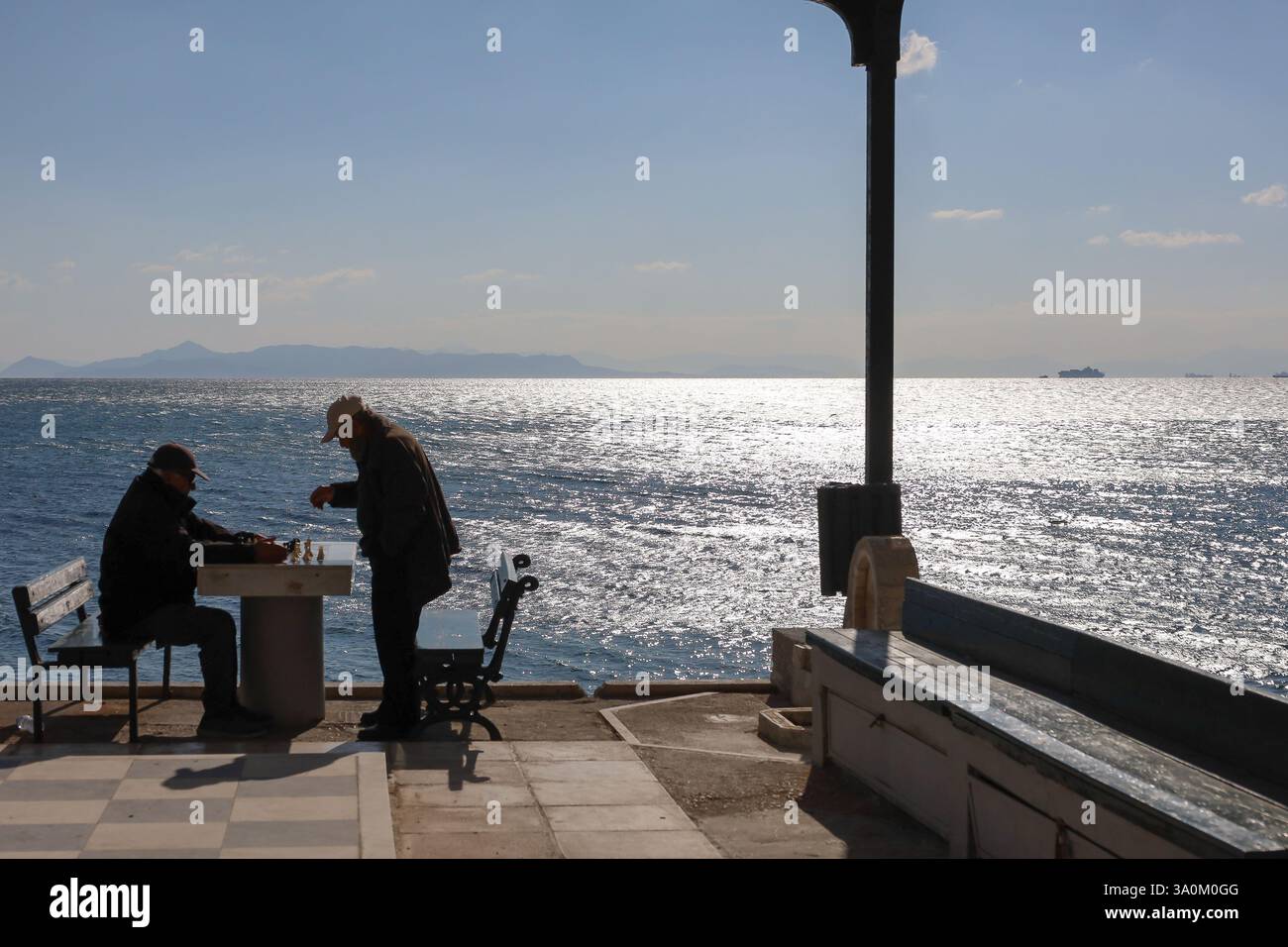 Athen, Griechenland - 4. März 2025. Silhouetten zweier älterer Männer, die Schach am Meer spielen Stockfoto