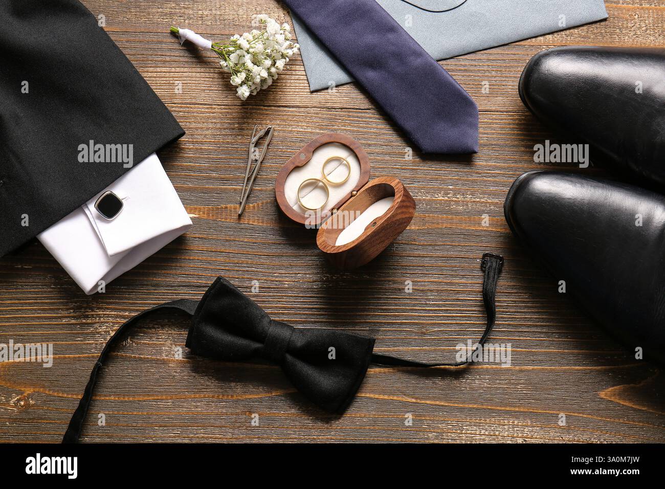 Box mit Ehering, Fliege und Boutonniere auf hölzernem Hintergrund. Draufsicht Stockfoto