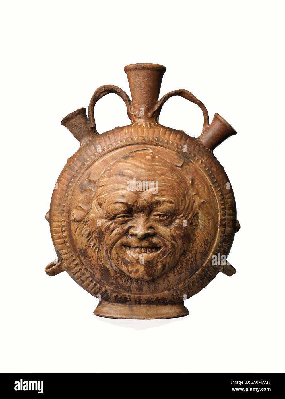 Flasche mit Gesicht um 1890 - glasiertes Steinzeug - Jean-Joseph Carriès Französisch - das grimmige Gesicht offenbart die Gaben des Künstlers als Bildhauer – seinen Beruf bevor er Keramiker wurde. Carriès schuf eine wichtige Serie von Masken, die vom japanischen Noh-Theater und den Wasserspeiern und geschnitzten Gesichtern der gotischen Kirchenarchitektur inspiriert wurden. Seine Steinzeugkolben mit Gesichtern sind ein Ableger dieser Produktion. Das bärtige Gesicht als Motiv auf einem Wasserkrug hat seinen Ursprung in deutschen Steingut-Gefäßen aus dem 16. Und 17. Jahrhundert, die als Beardman oder Bellarmine Krüge bekannt sind. Stockfoto