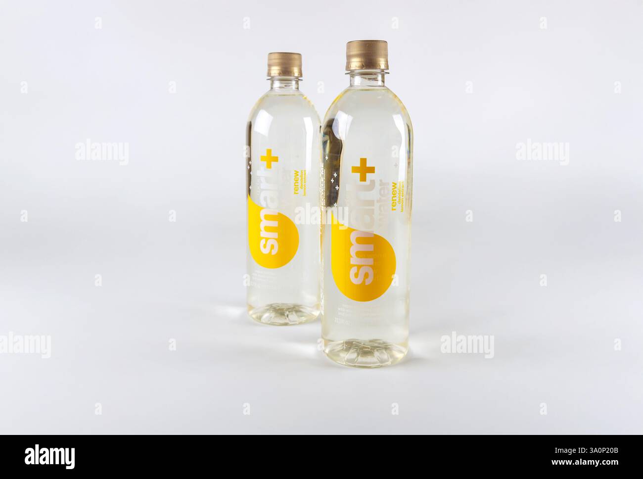 Durchsichtige Flaschen mit Etiketten mit intelligentem Logo, gefüllt mit klarer Flüssigkeit auf einfachem weißem Hintergrund Stockfoto