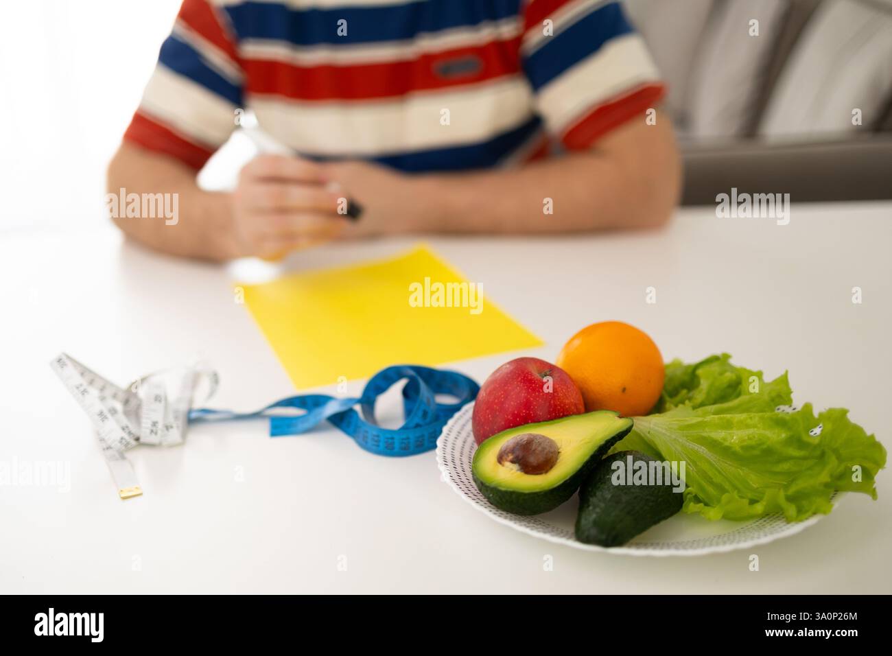 Eine Person, die sorgfältig nahrhafte Mahlzeiten mit verschiedenen frischen Produkten und verschiedenen Messgeräten plant Stockfoto