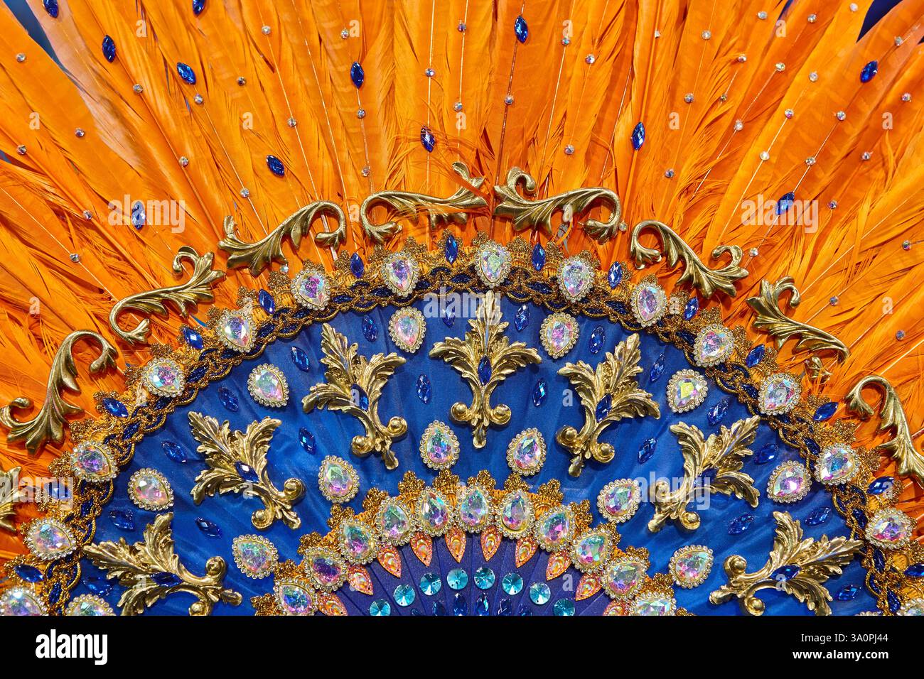 Handgefertigter Fächer mit orangefarbenen Federn und Schmuck. Karnevalszeit Stockfoto