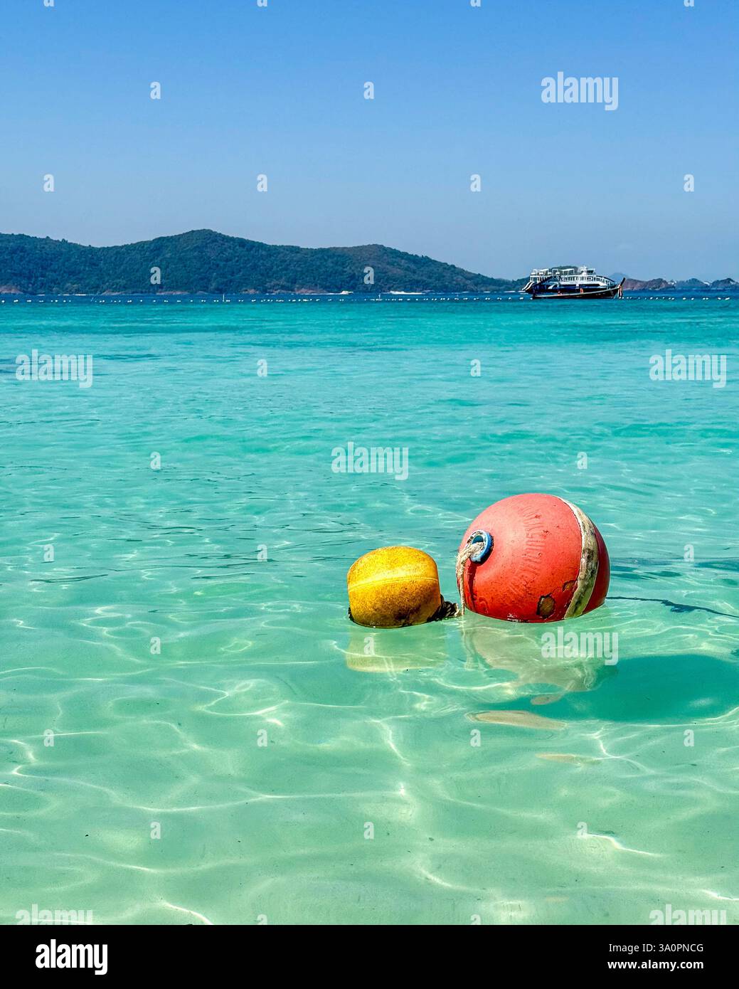 Schwimmende Bojen in kristallklarem Wasser 2 zwei farbenfrohe Bojen, eine rote und eine gelbe, schweben sanft auf dem atemberaubenden türkisfarbenen Meer. Im Hintergrund wird A angezeigt - Smartphone-aufgenommenes Stockfoto
