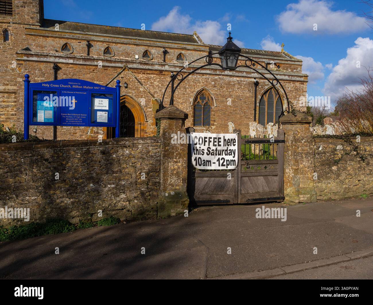 Außenansicht der Pfarrkirche des Heiligen Kreuzes, Milton Malsor, Northamptonshire, Großbritannien; mit einem Werbespot für einen Samstagmorgen Stockfoto