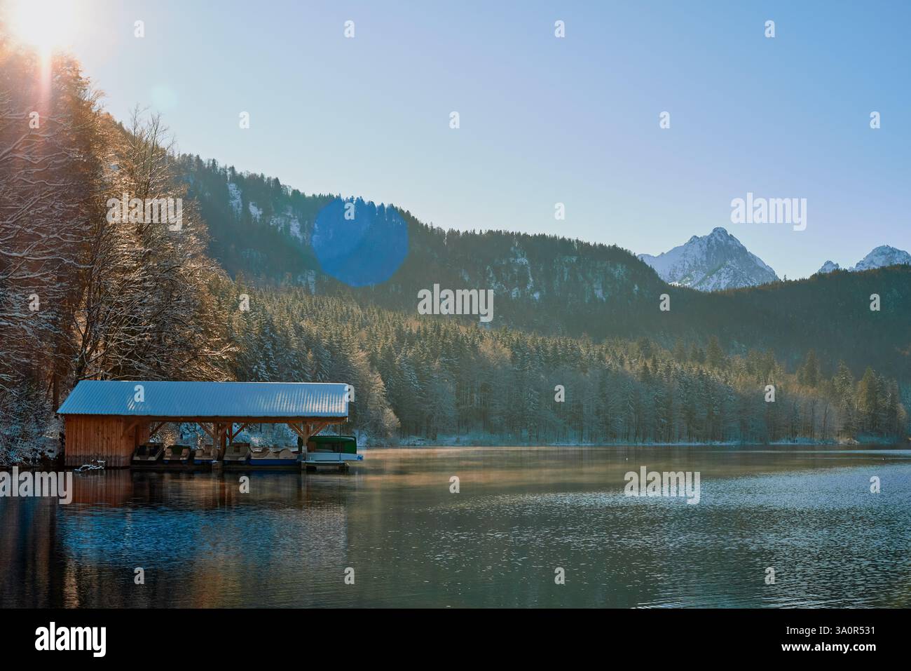 Dieses Foto zeigt eine ruhige Winterszene an einem ruhigen See. Das Bild zeigt ein hölzernes Dock, das in das Wasser hineinreicht und teilweise mit einem s bedeckt ist Stockfoto