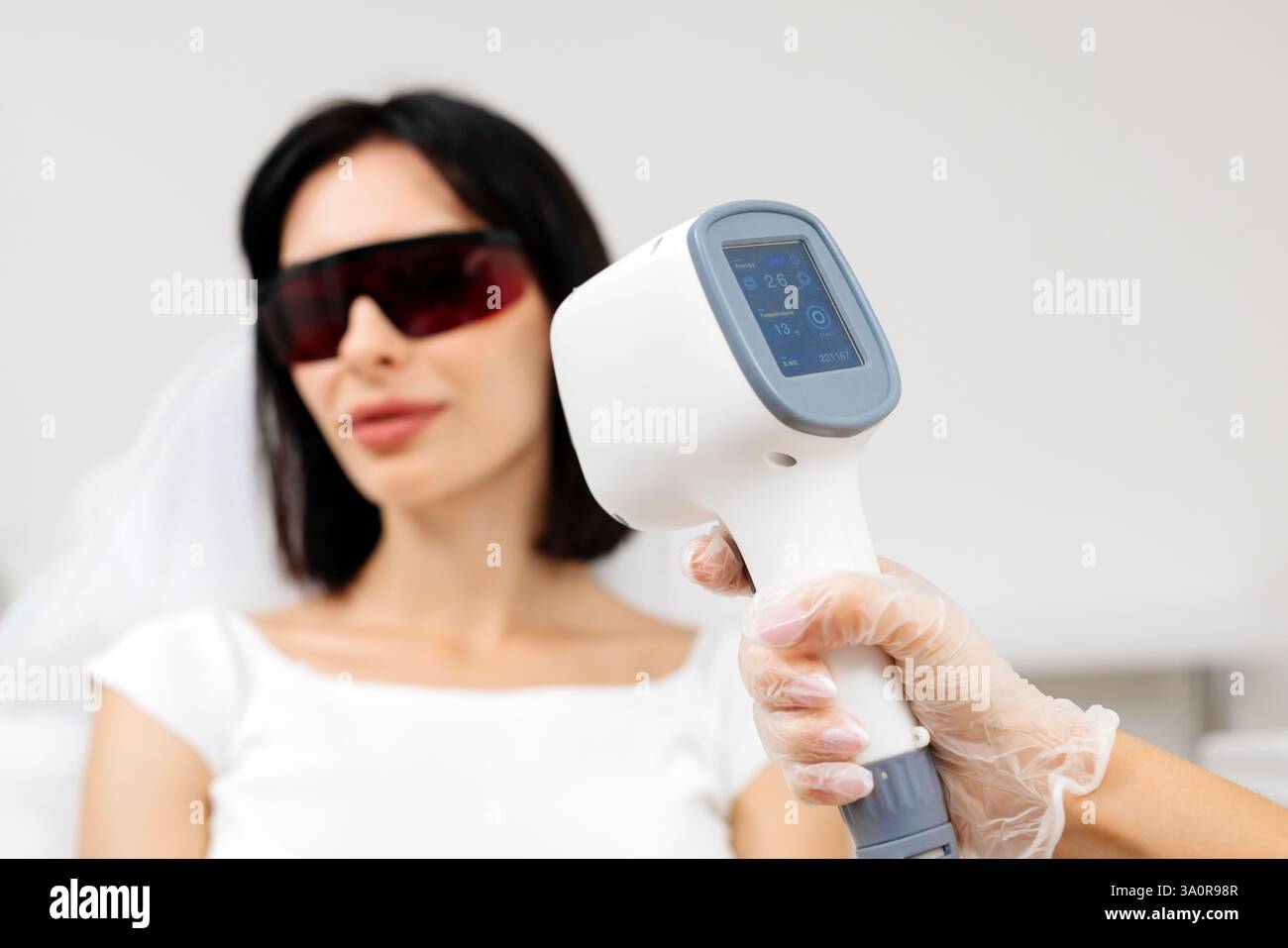 Die Therapeutin/Kosmetikerin führt eine Laserbehandlung auf dem Gesicht einer Frau in einer Schönheitsklinik durch. Nahaufnahme. Das Konzept der Werbung gesund Stockfoto Die Therapeutin/Kosmetikerin führt eine Laserbehandlung auf dem Gesicht einer Frau in einer Schönheitsklinik durch. Nahaufnahme. Das Konzept der Werbung gesund Stockfoto