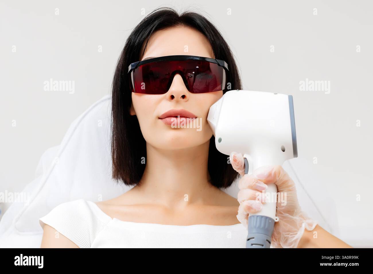 Die Therapeutin/Kosmetikerin führt eine Laserbehandlung auf dem Gesicht einer Frau in einer Schönheitsklinik durch. Nahaufnahme. Das Konzept der Werbung gesund Stockfoto Die Therapeutin/Kosmetikerin führt eine Laserbehandlung auf dem Gesicht einer Frau in einer Schönheitsklinik durch. Nahaufnahme. Das Konzept der Werbung gesund Stockfoto